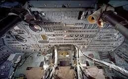 What We Owe to the Apollo Program in the 21st Century sitting cracked and slightly dusty on a messy home desk next to an open laptop showing